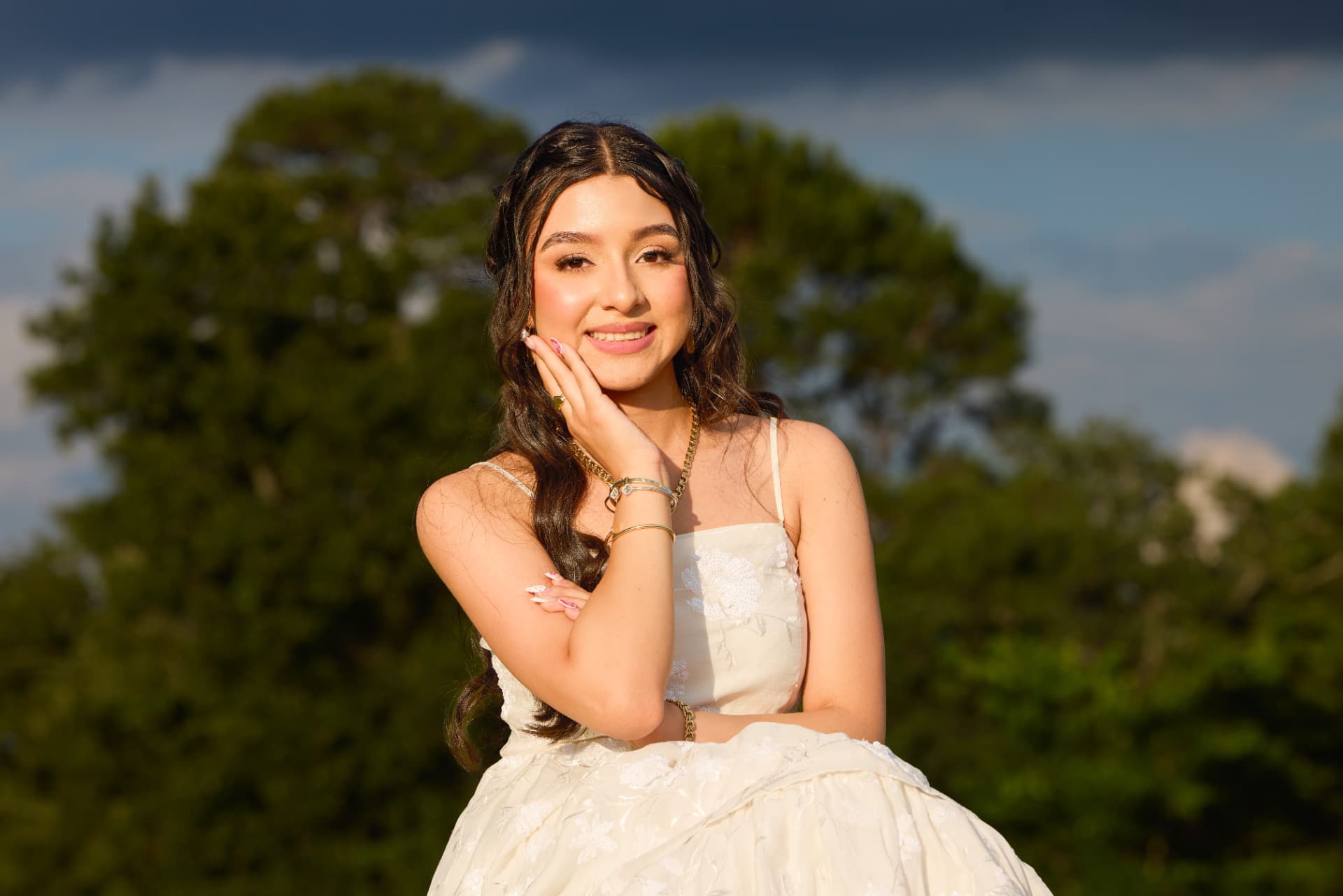 Jihan Jolie sonriendo con vestido blanco entre los árboles